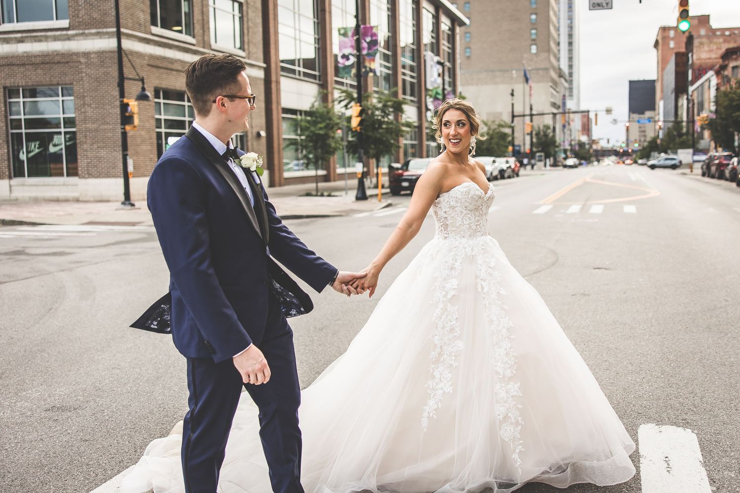 Wedding couple playfully poses in middle of downtown street surrounded by urban architecture.