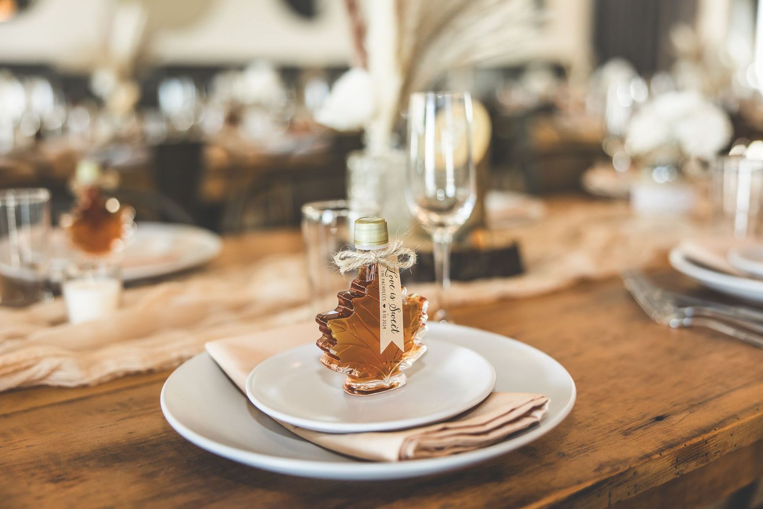 Close-up of place settings with glassware on rustic wooden tables.