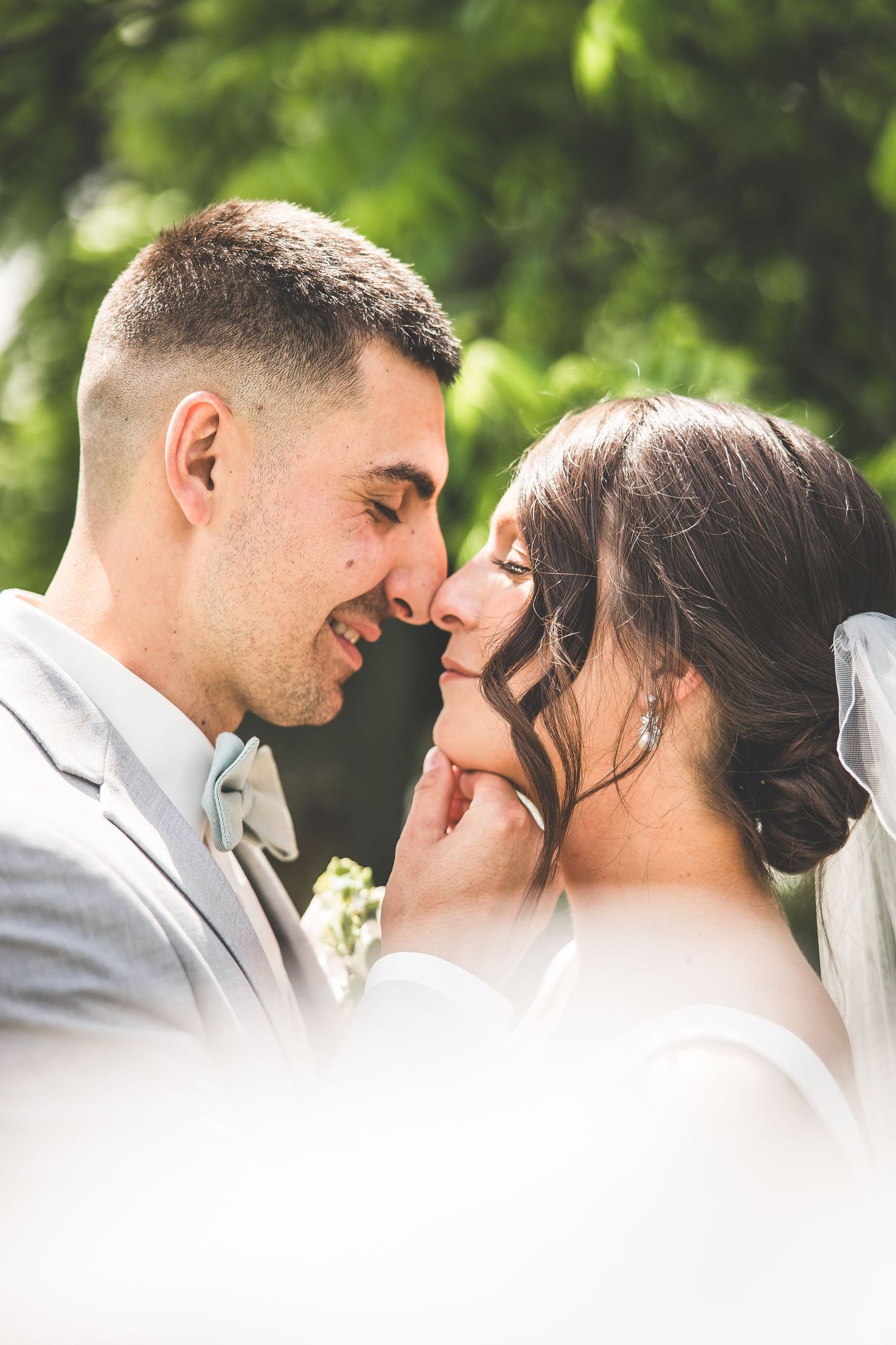 Intimate close-up of wedding couple sharing a tender moment outdoors.