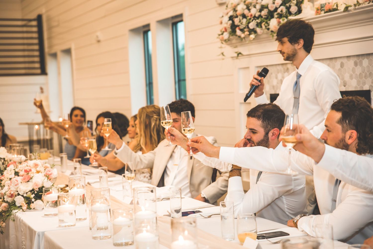 Wedding reception guests seated at decorated tables during dinner and toasts.