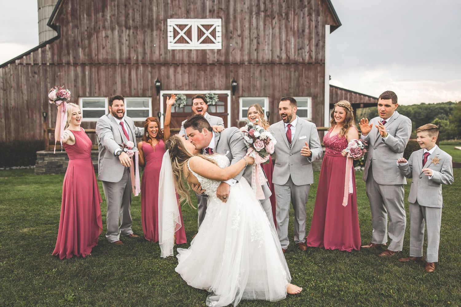 Celebration outside Twin Silos barn with wedding party in burgundy and gray attire.