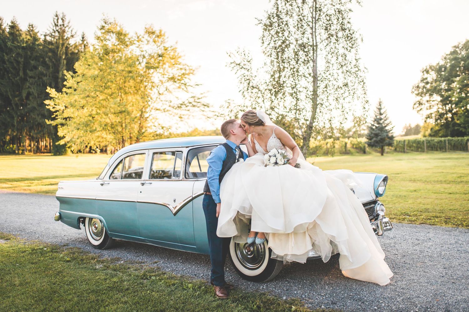 Classic turquoise vintage car decorated for wedding with flowing white dress visible.