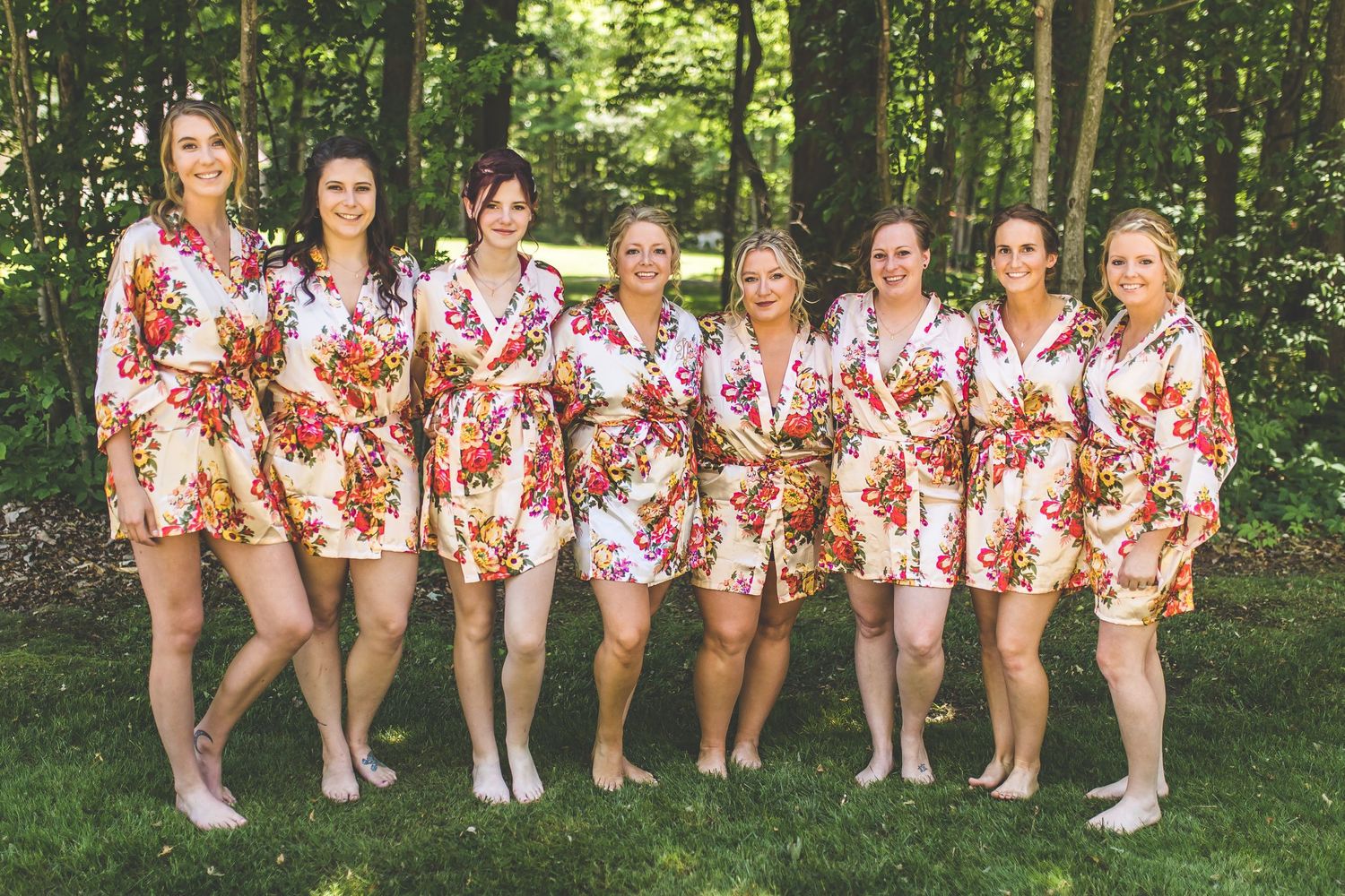 Group wearing matching floral robes standing together in woodland setting.