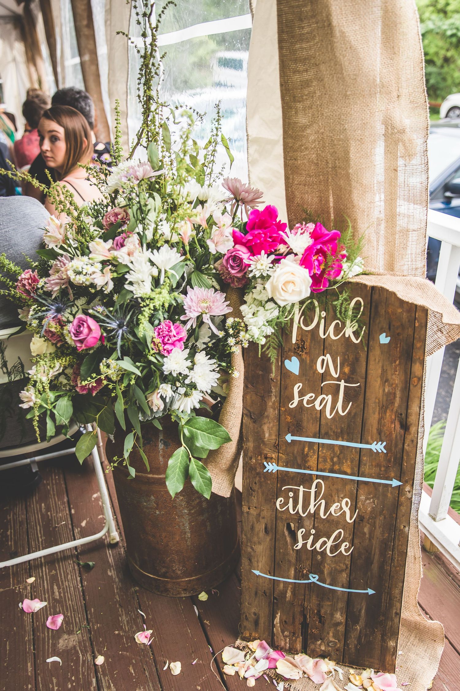 Rustic wooden seating chart display decorated with pink and white floral arrangements.