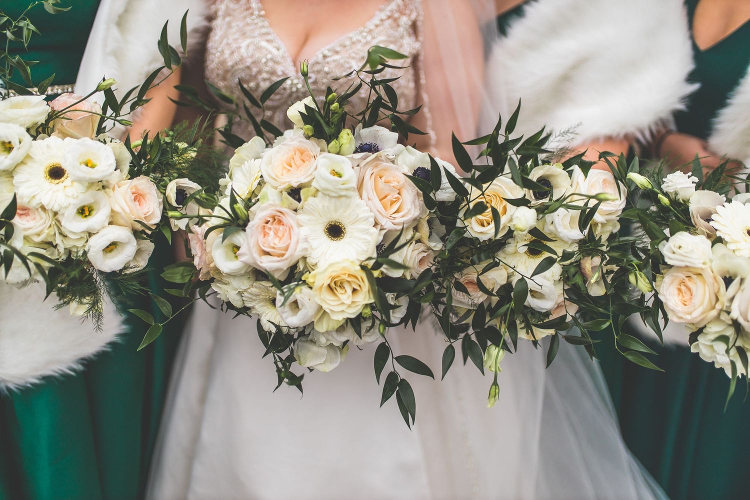 Multiple wedding bouquets featuring white and blush flowers with greenery.