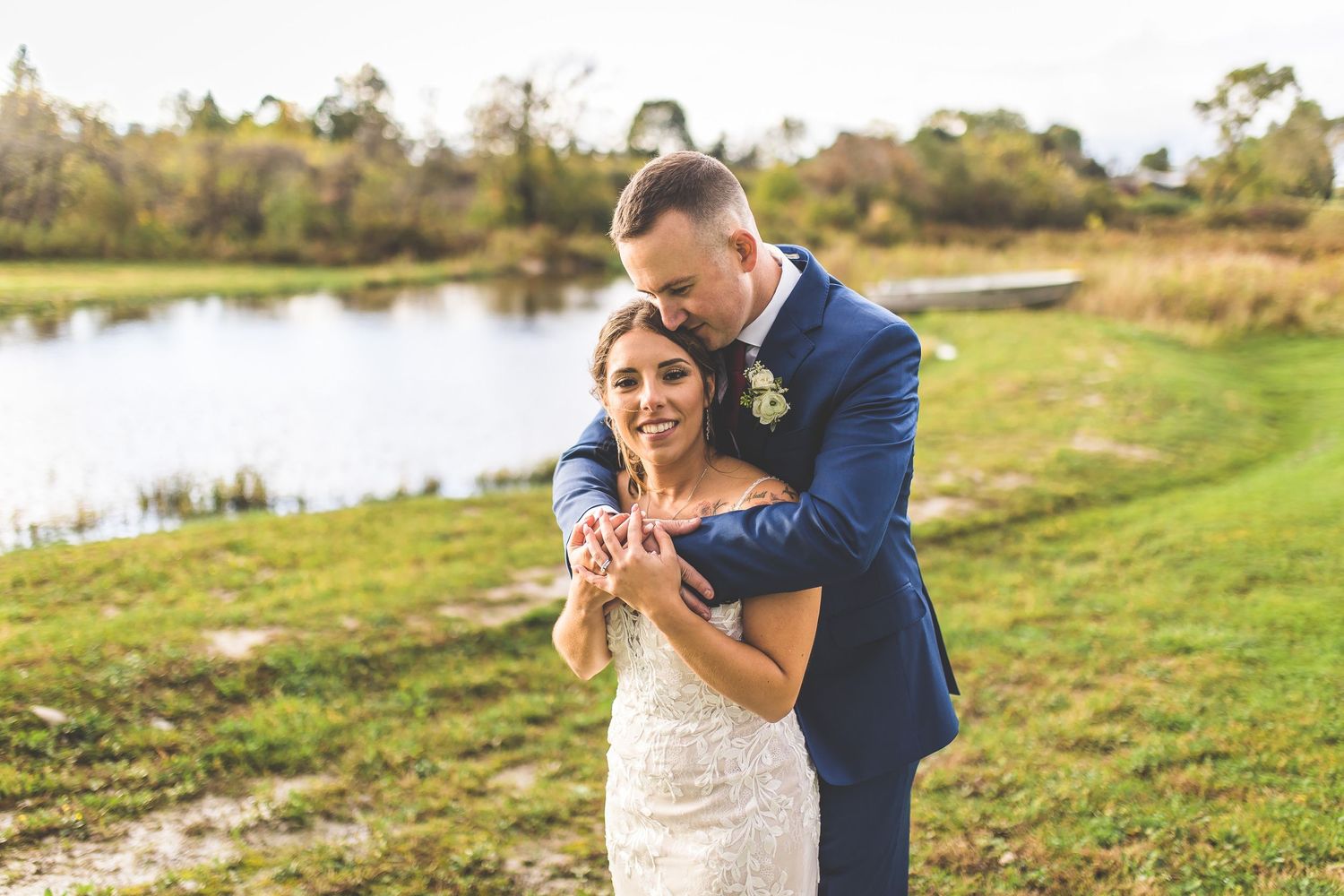 Wedding couple shares candid moments during outdoor photo session near water.