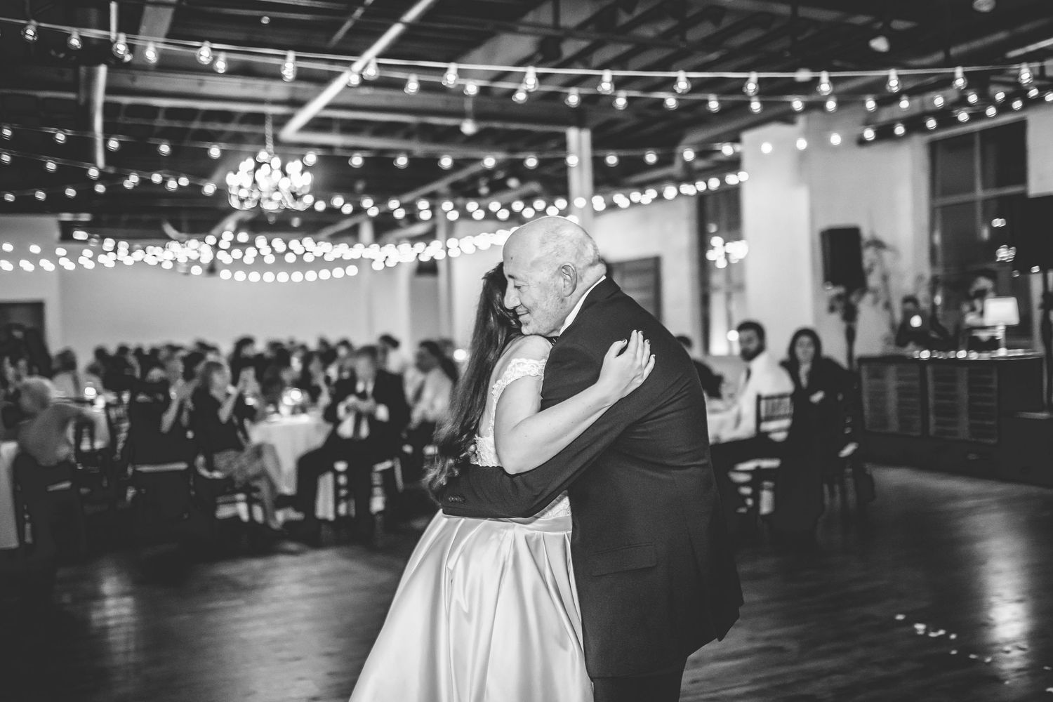 Wedding reception venue decorated with string lights and white drapery for evening celebration.