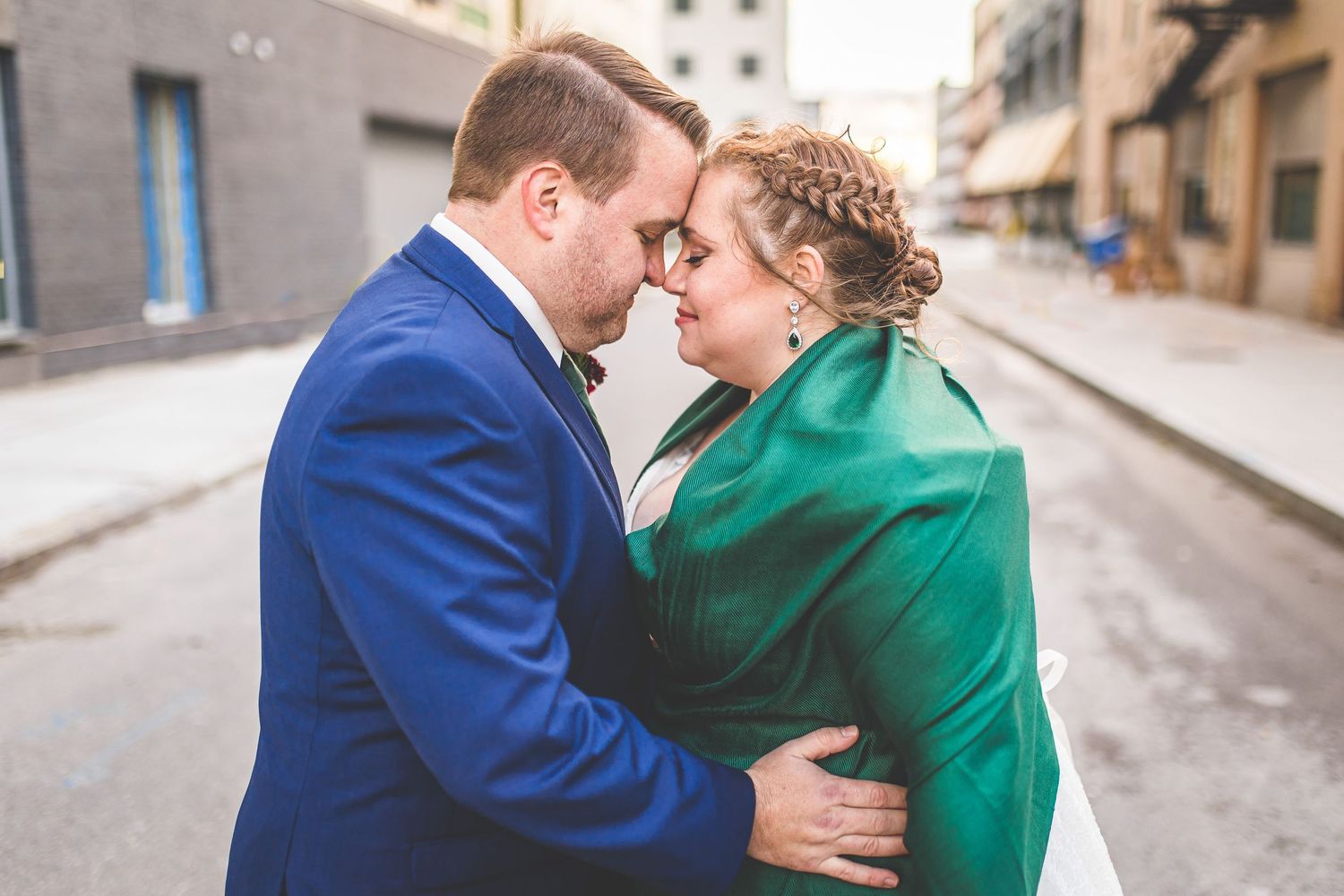 Tender moment between newlyweds as they embrace, with bride wearing distinctive emerald wrap.