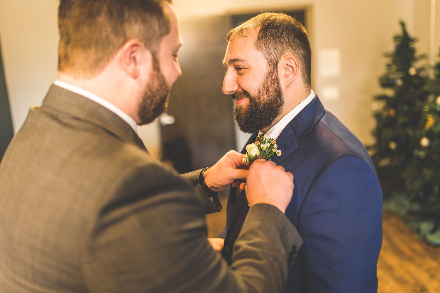 Groomsmen adjusting ties and helping each other prepare in formal attire.