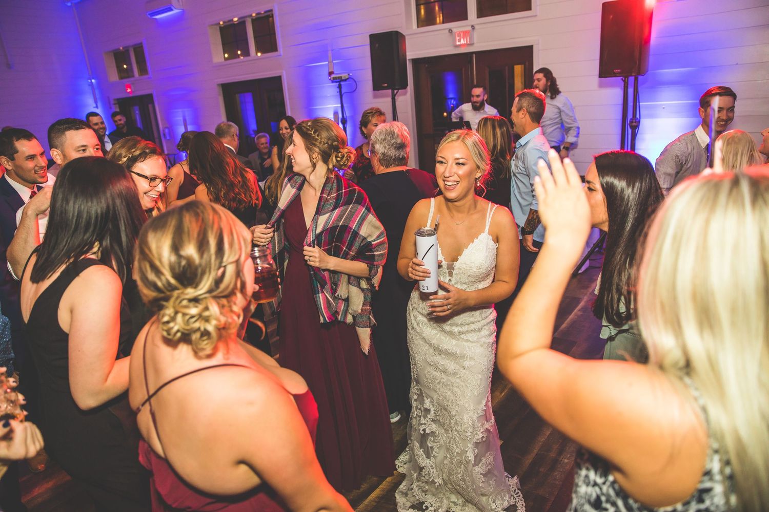 Wedding reception dance floor filled with energetic guests under purple and blue lighting.