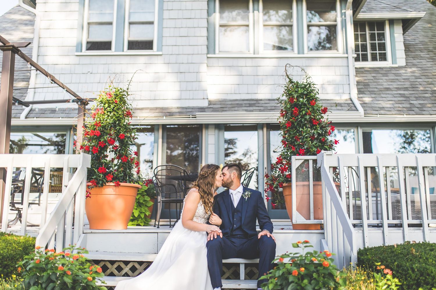 Intimate moment shared on porch steps with red climbing flowers in planters.