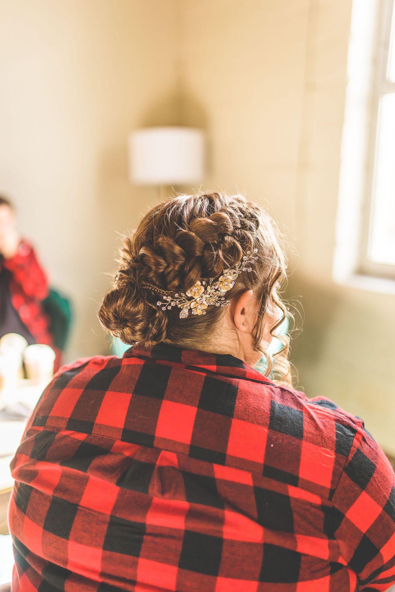 Back view of person wearing red and black buffalo plaid flannel with styled hair and hair accessories.