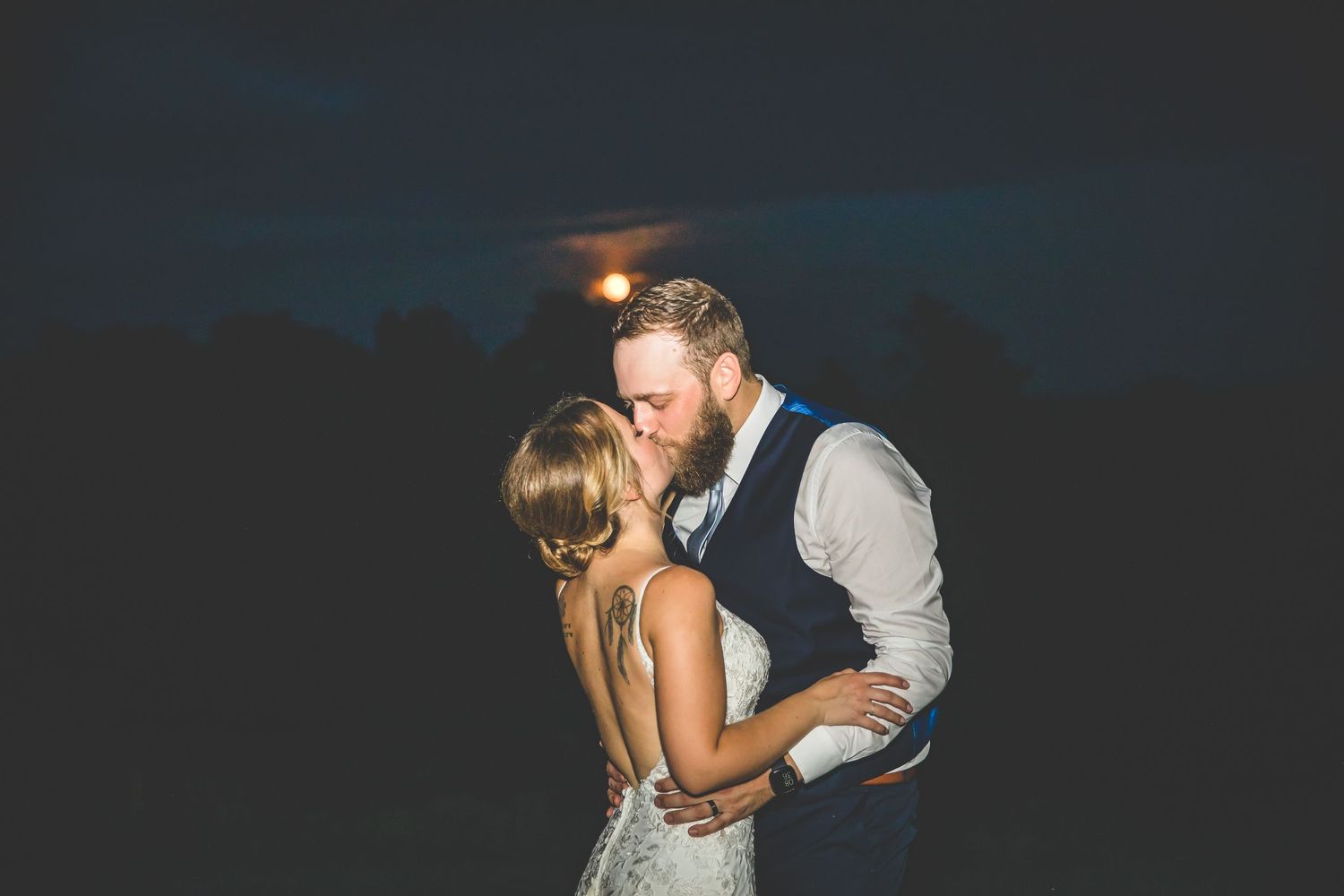 Couples sharing romantic dances under dim lighting at an evening wedding reception.