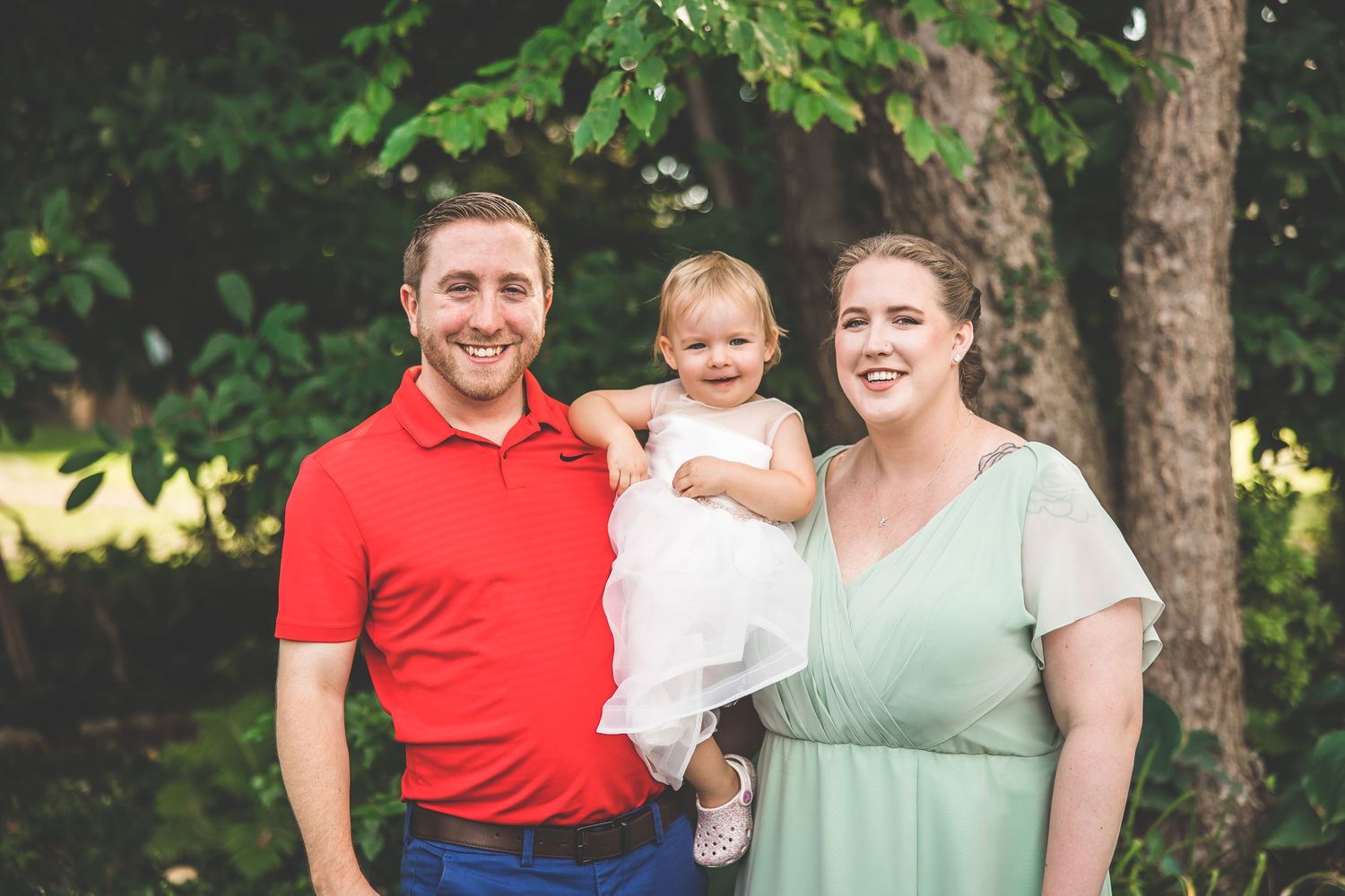 Family portrait taken outdoors with casual attire against a natural background.