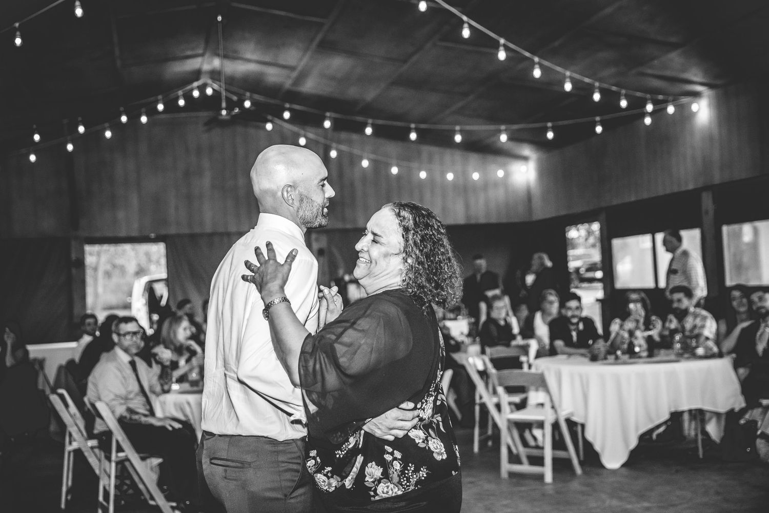 Wedding reception dance floor filled with guests under twinkling string lights.