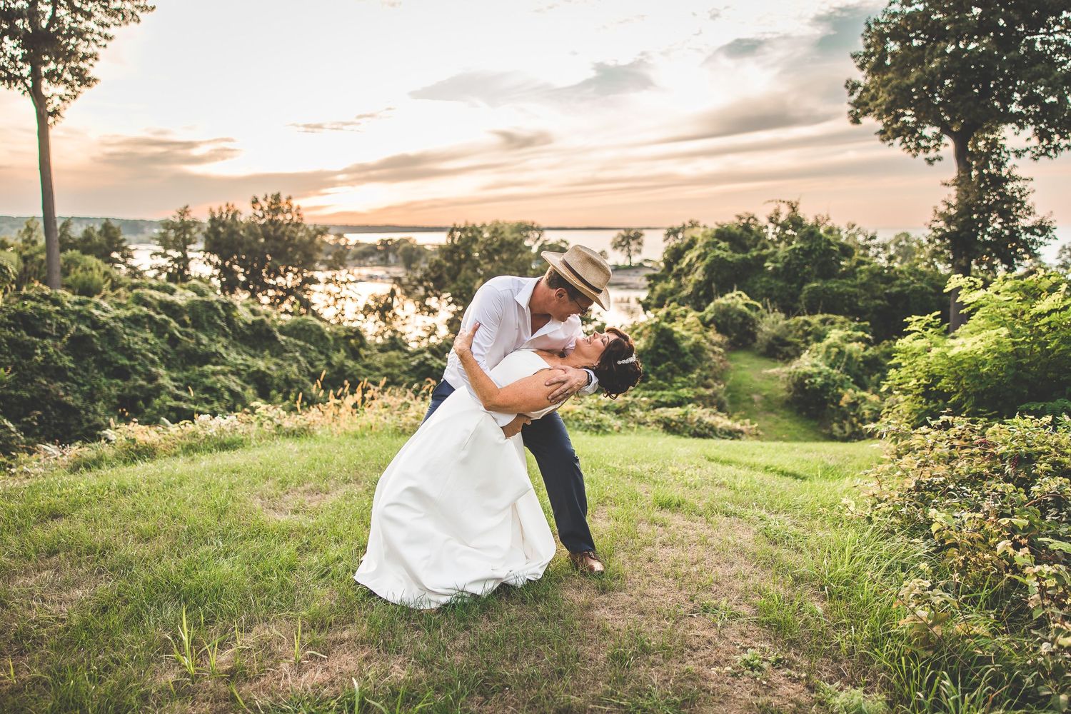 Scenic outdoor wedding photos captured against a beautiful sunset and rolling hills.