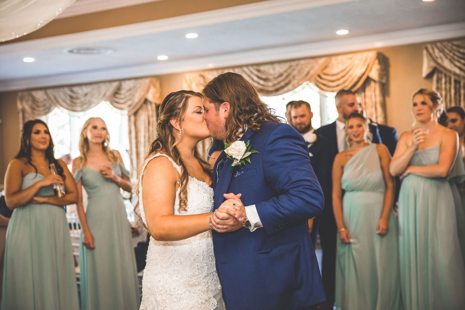 Wedding party members in blue and mint green attire gather for celebration photos.