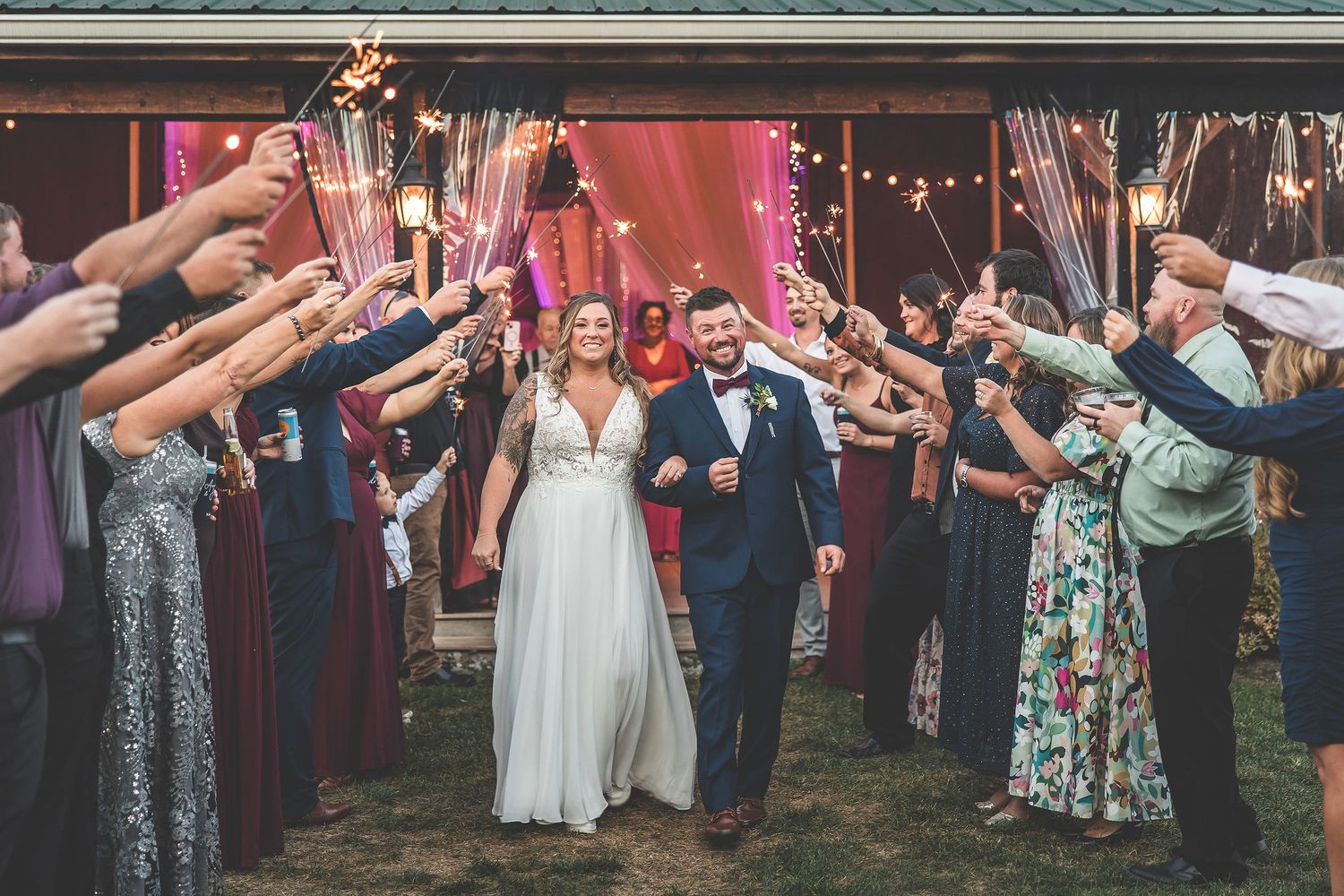 Wedding exit through tunnel of guests holding sparklers at night.