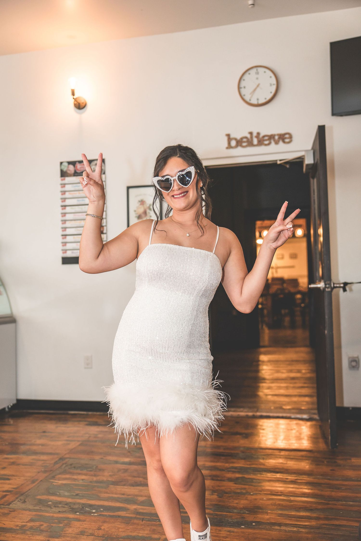 Playful sequence of someone in a white feathered dress dancing in a bright room with wooden floors.