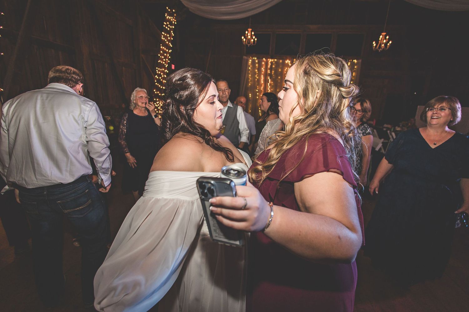 Two guests share a moment during a reception in a dimly lit barn venue.