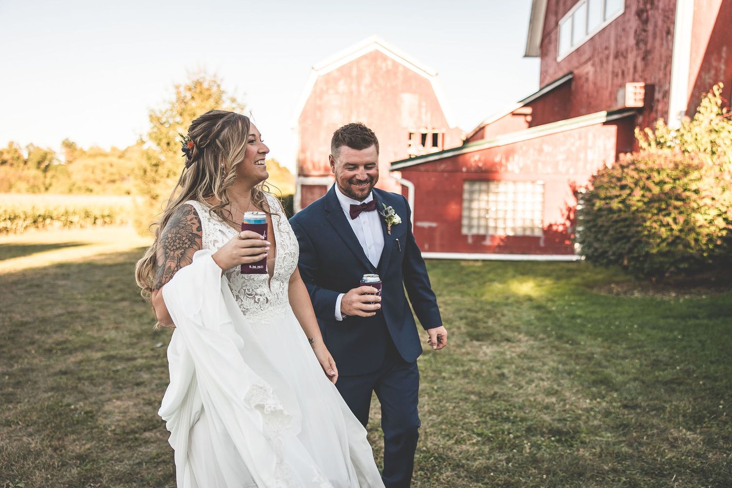 Romantic wedding portraits by rustic barn with golden sunlight filtering through trees.