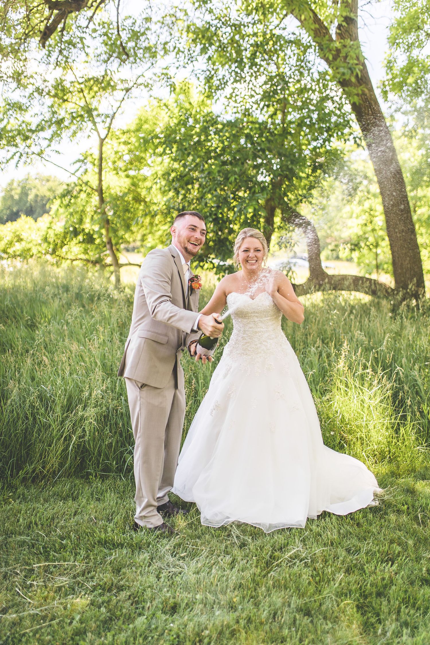 Wedding couple shares joyful moment together in sunlit garden setting.