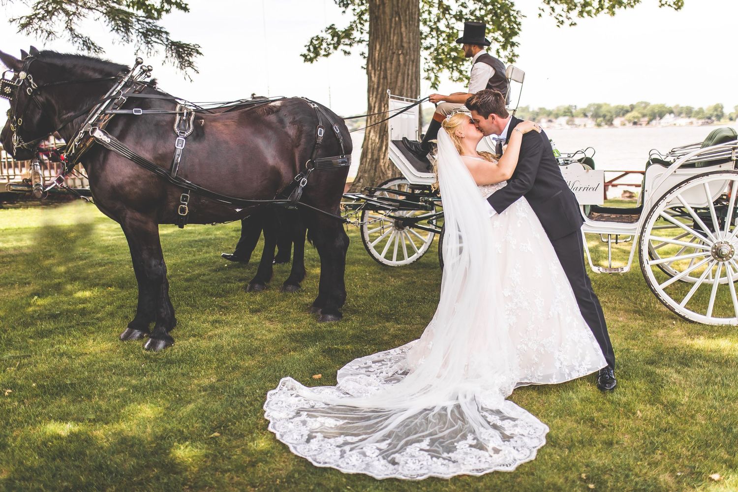 Romantic wedding scene with horse-drawn carriage and flowing bridal gown train.