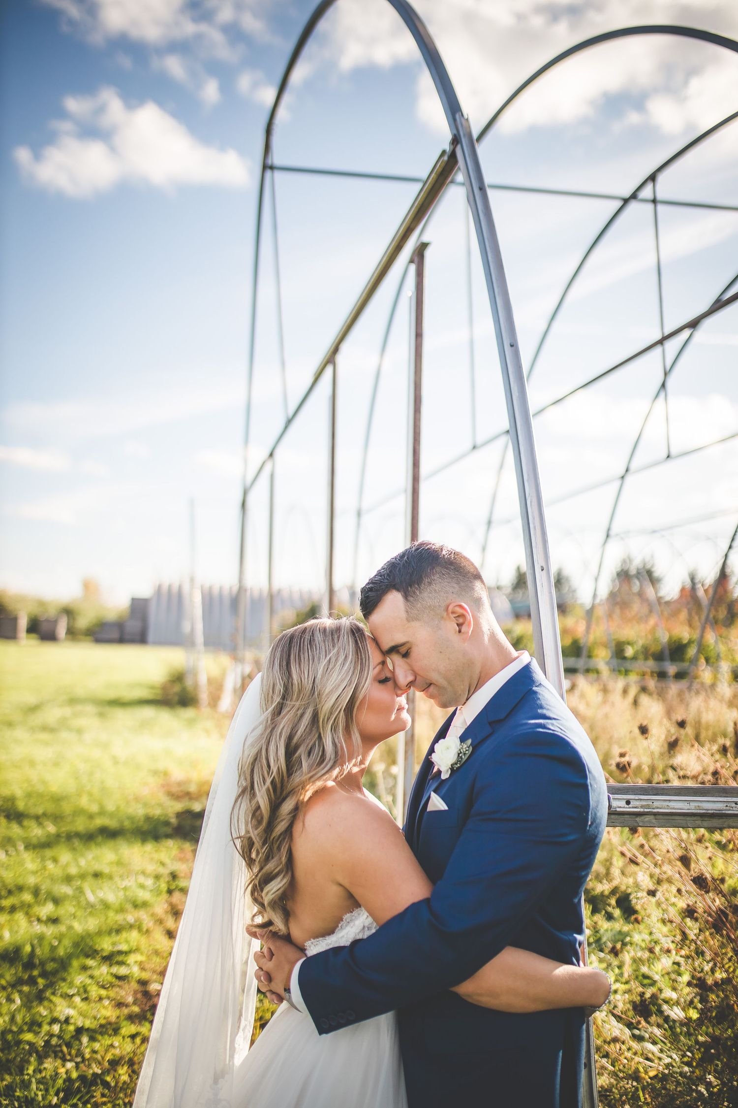 Couple shares a tender moment under metal arches in golden afternoon sunlight.