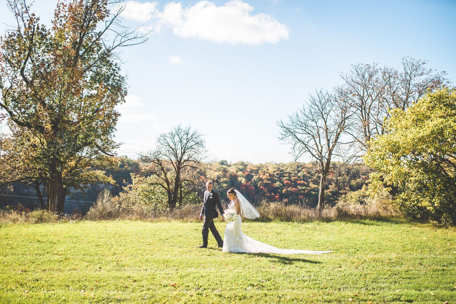 Wedding photography session in a sunny autumn field with trees and blue skies.