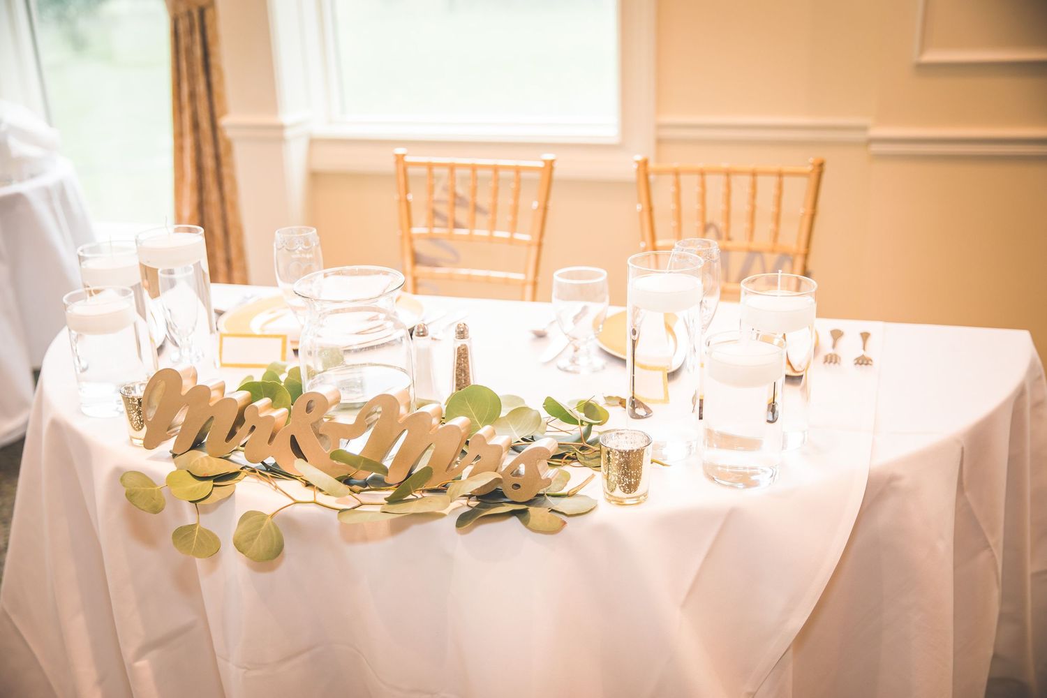 Elegant wedding reception tables with white linens and gold accents.
