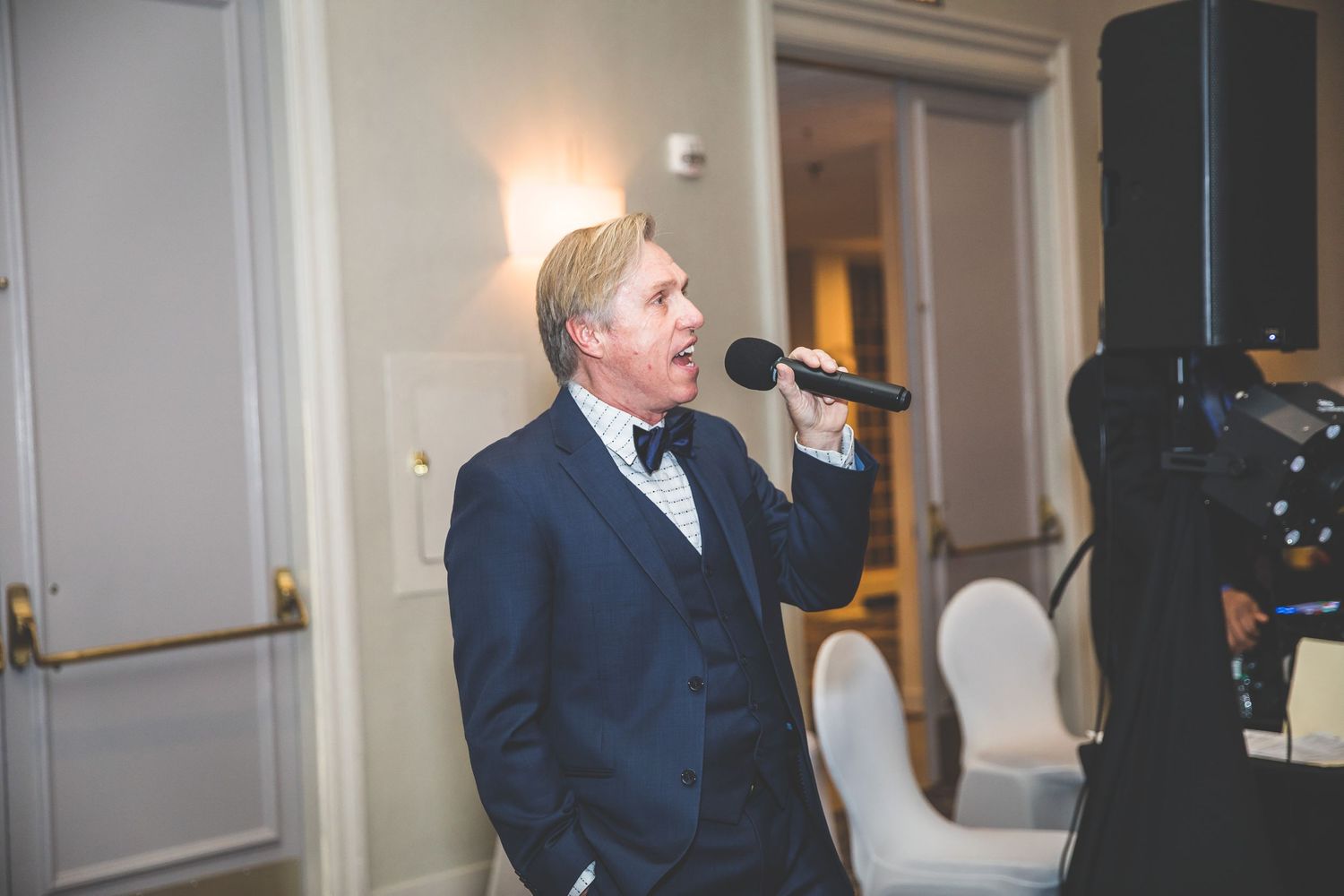 Wedding singer performs in a navy suit at an elegant reception venue.