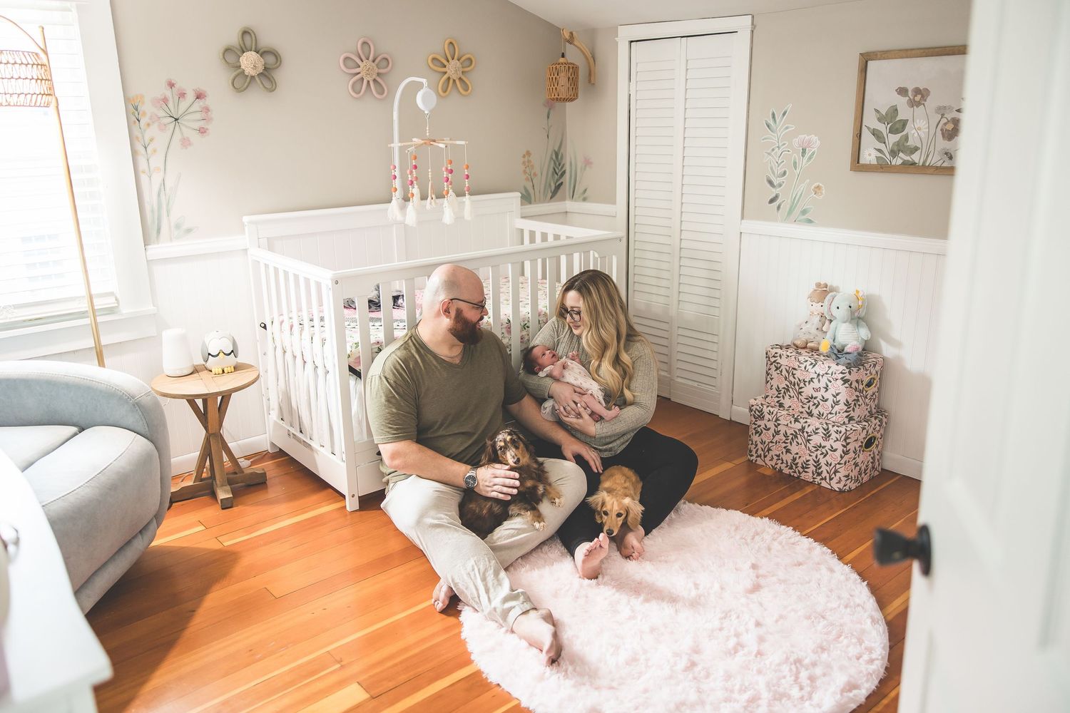 Cozy family moment in neutral-toned nursery with white crib.