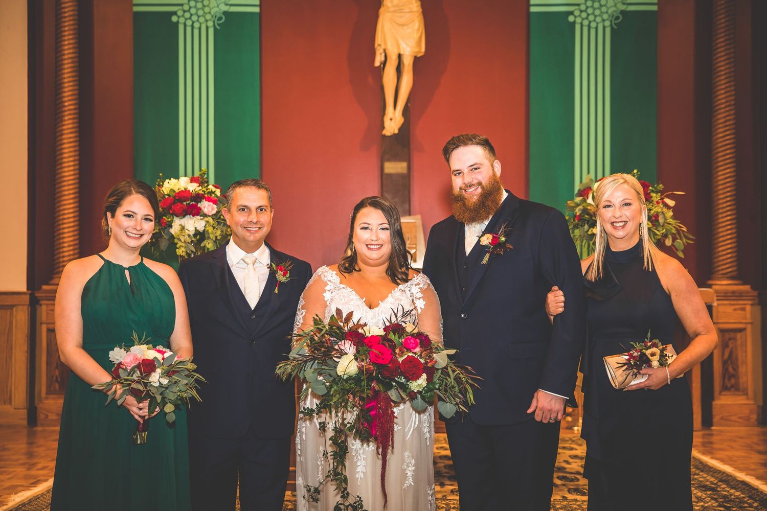Wedding party gathered in church sanctuary with decorative columns and religious symbols.