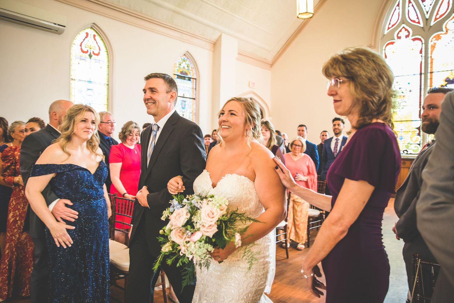 Wedding guests gather in a bright church interior during a ceremony.