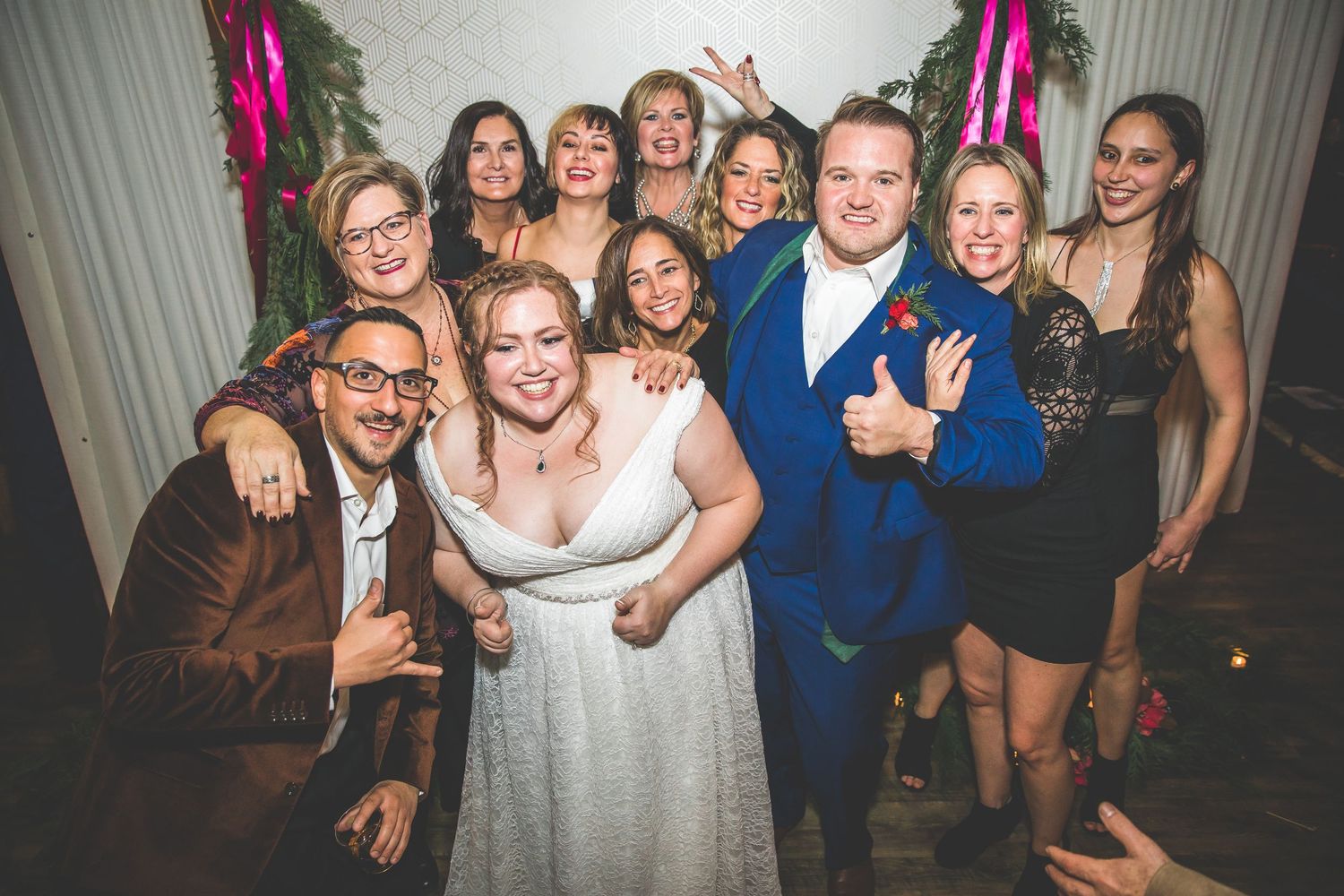Lively wedding reception with guests dancing and celebrating under decorative lighting.