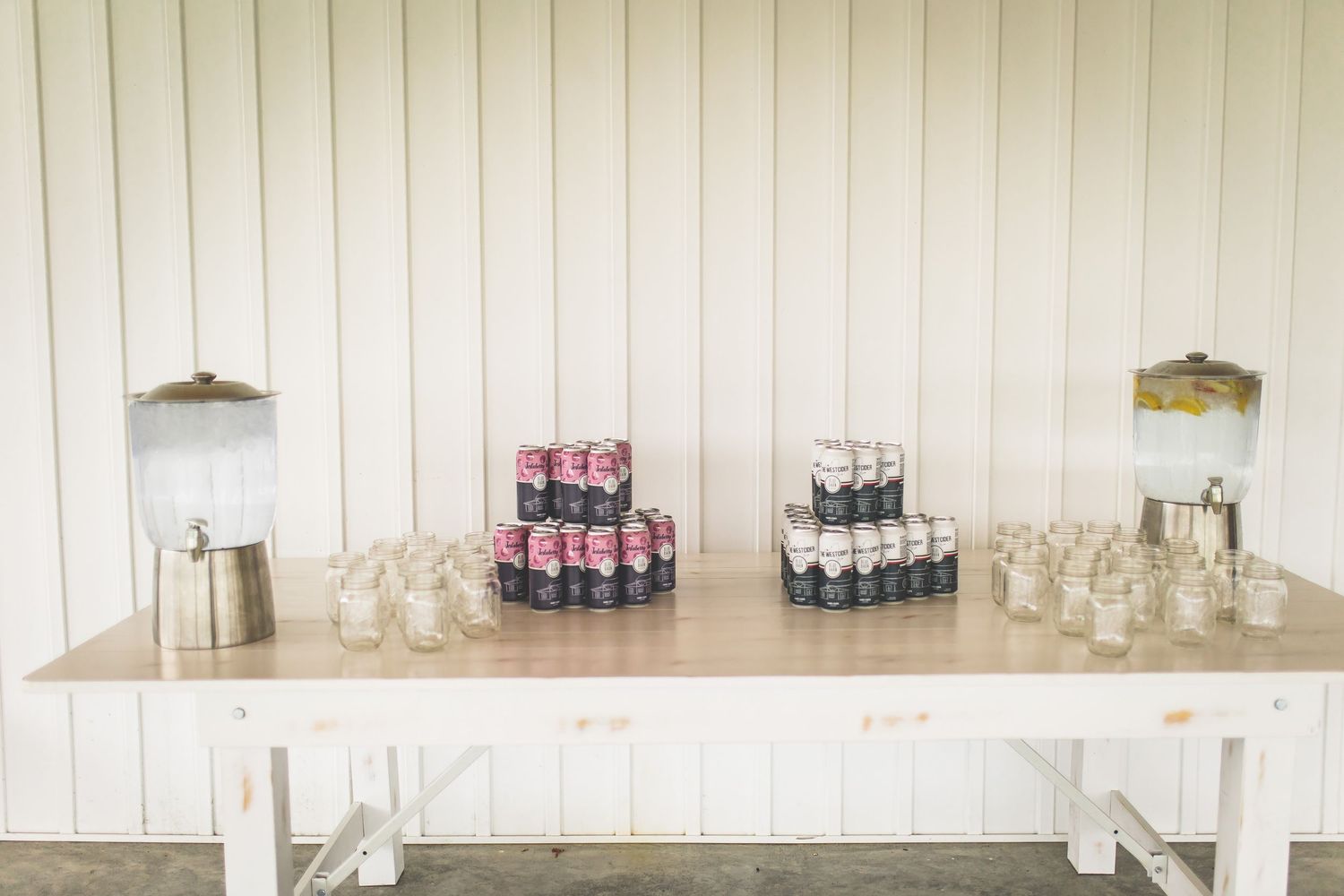 White rustic reception space with bar setup and glassware displays.