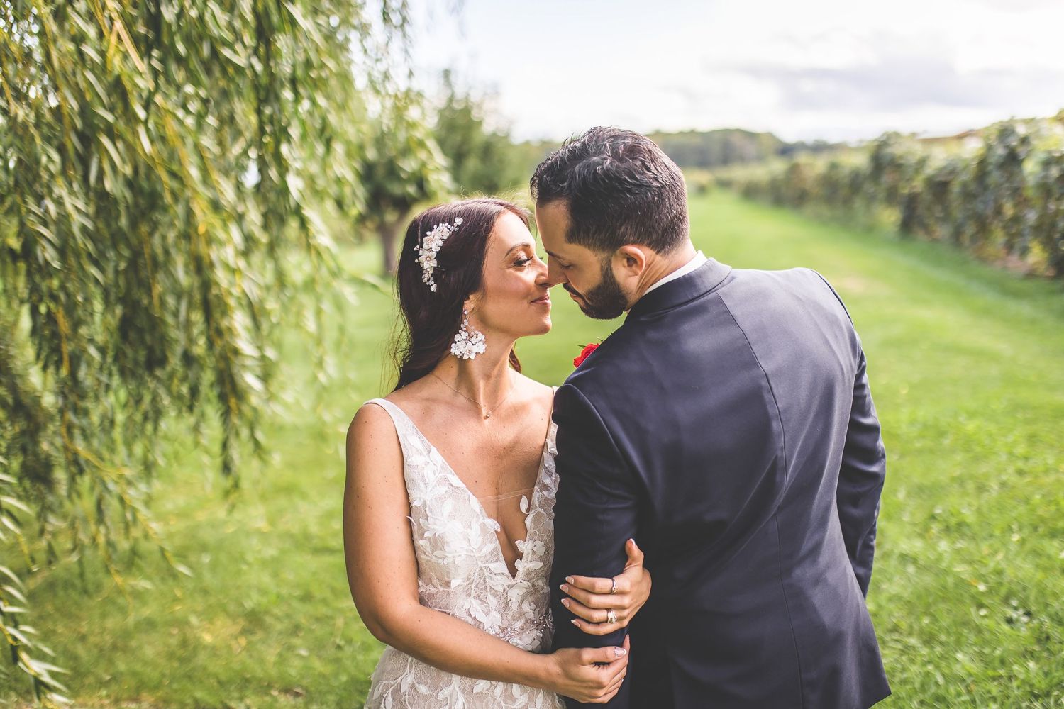 A romantic moment captured between a couple in formal attire under a weeping willow tree.