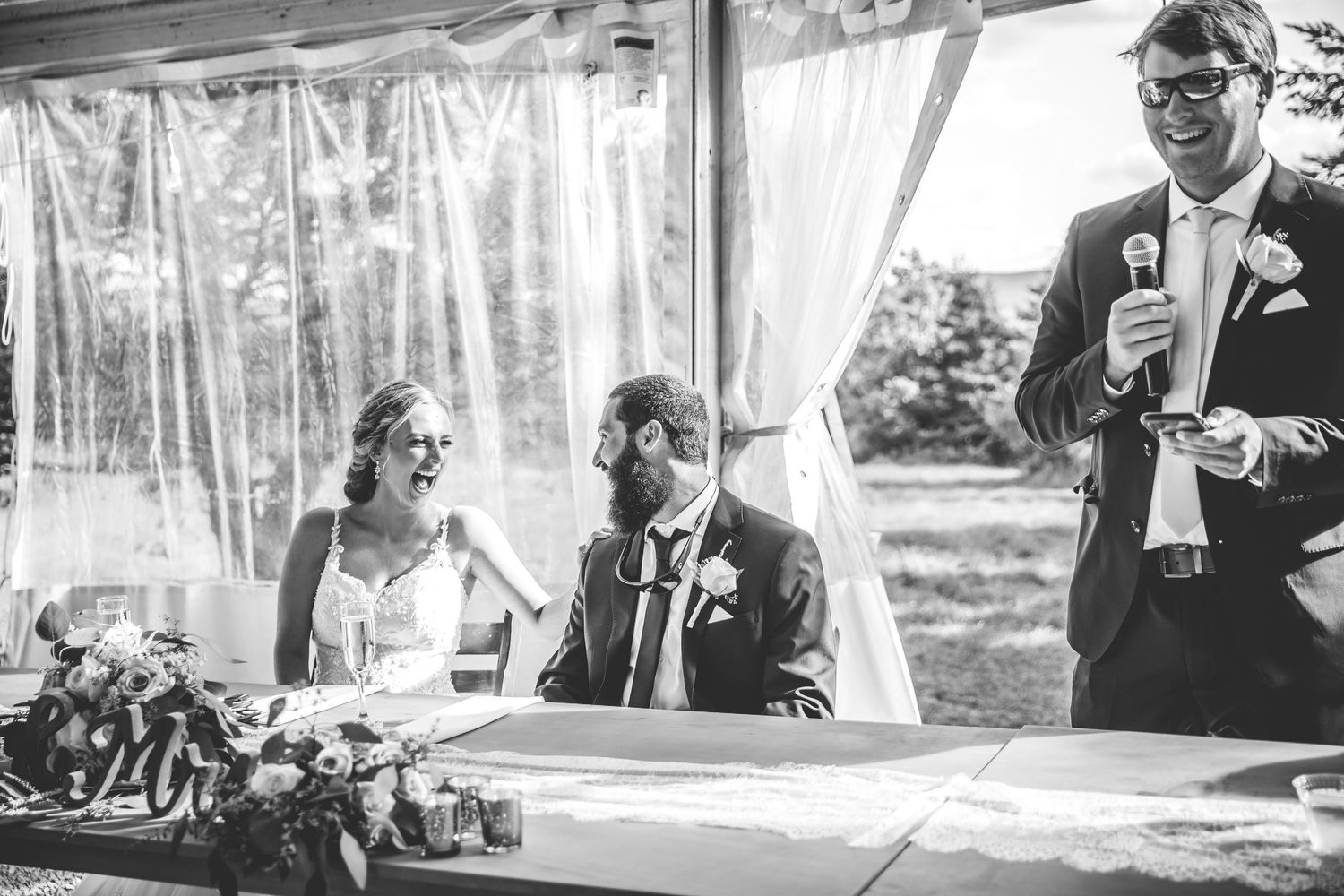 Wedding guests enjoying speeches and toasts during outdoor reception.