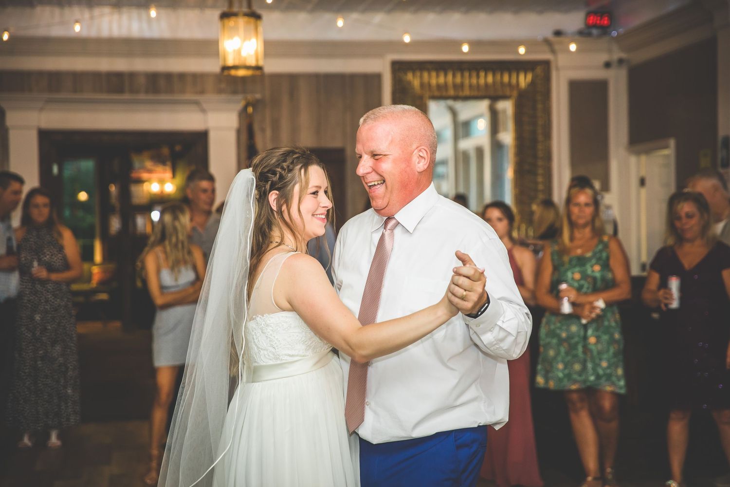 A bride in white dances with a partner during a romantic wedding celebration.