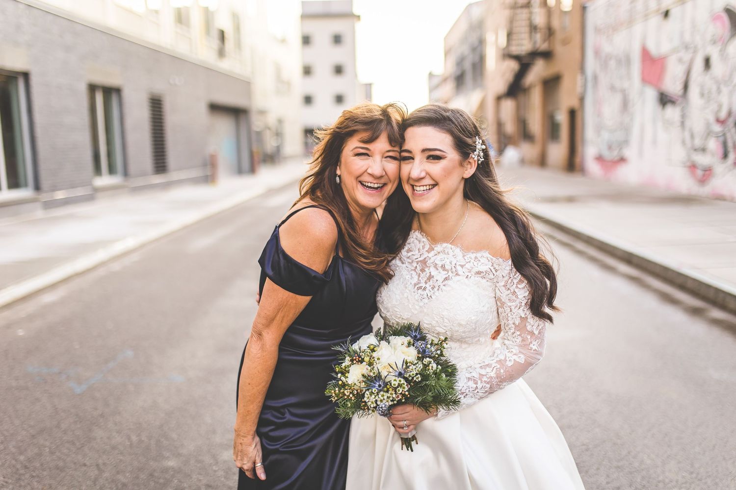 Wedding group shares joyful moment together on industrial city street.