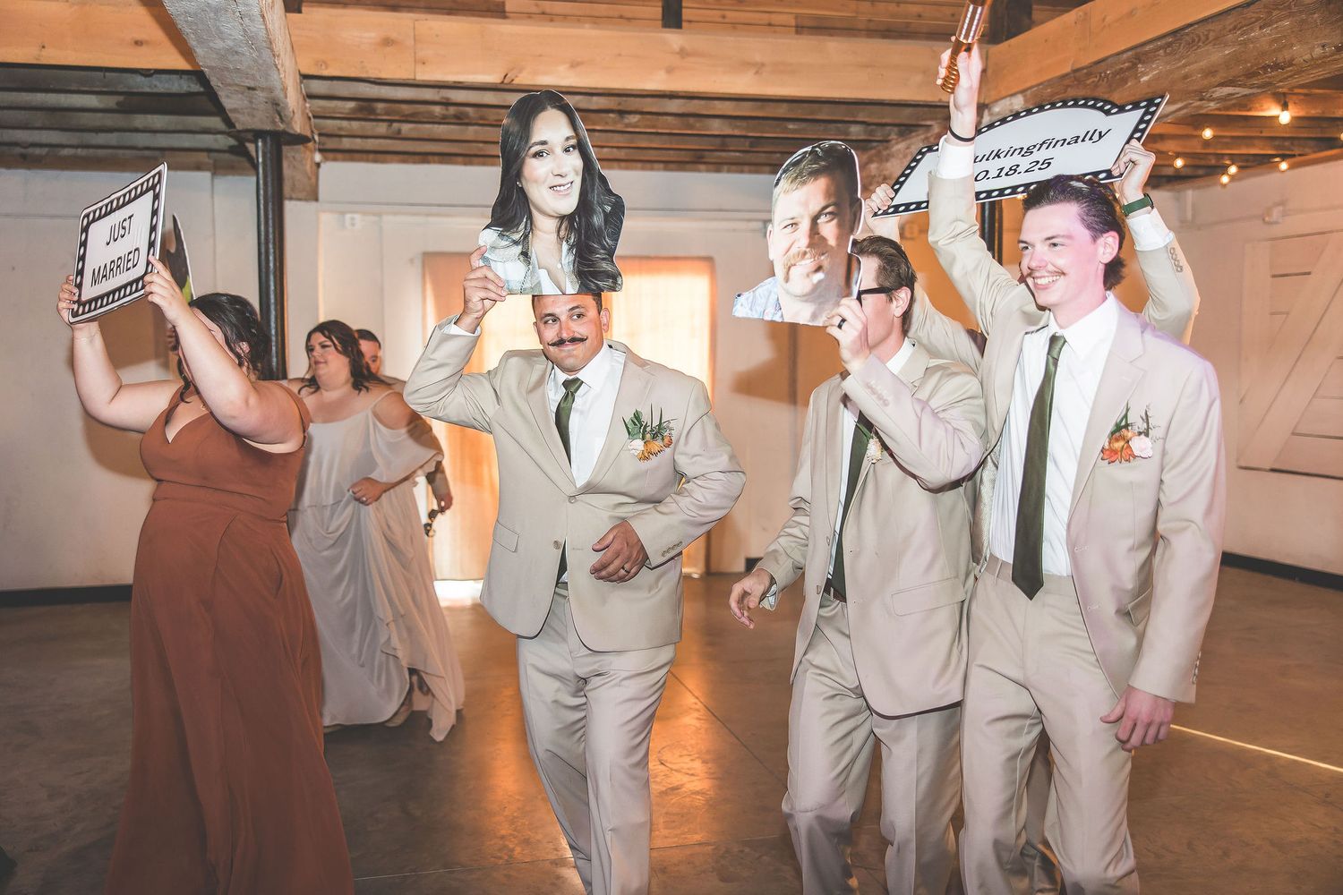 Wedding celebration with guests holding fun photo props and signs on dance floor.