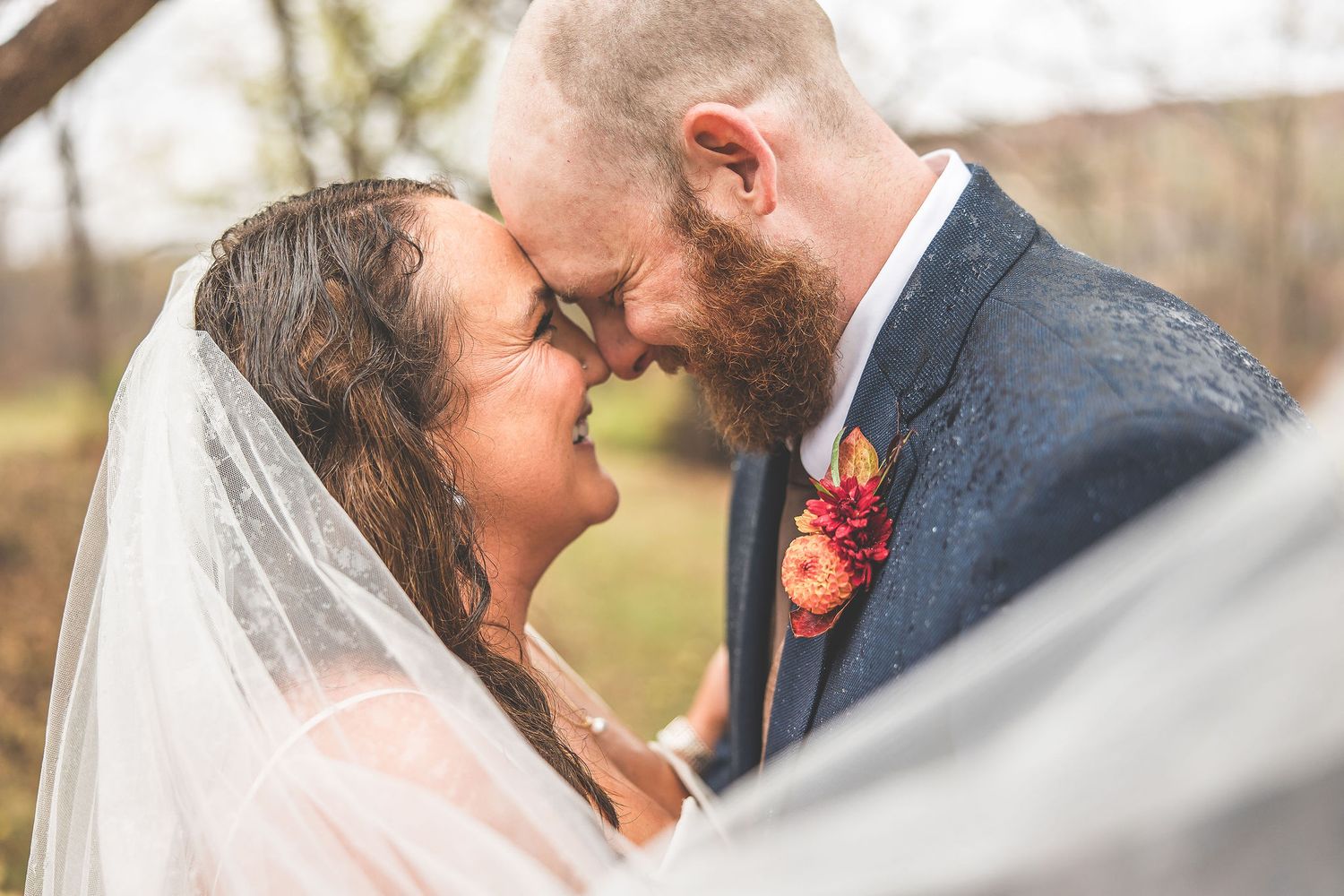 An intimate wedding portrait showing the couple sharing a tender moment under a veil.