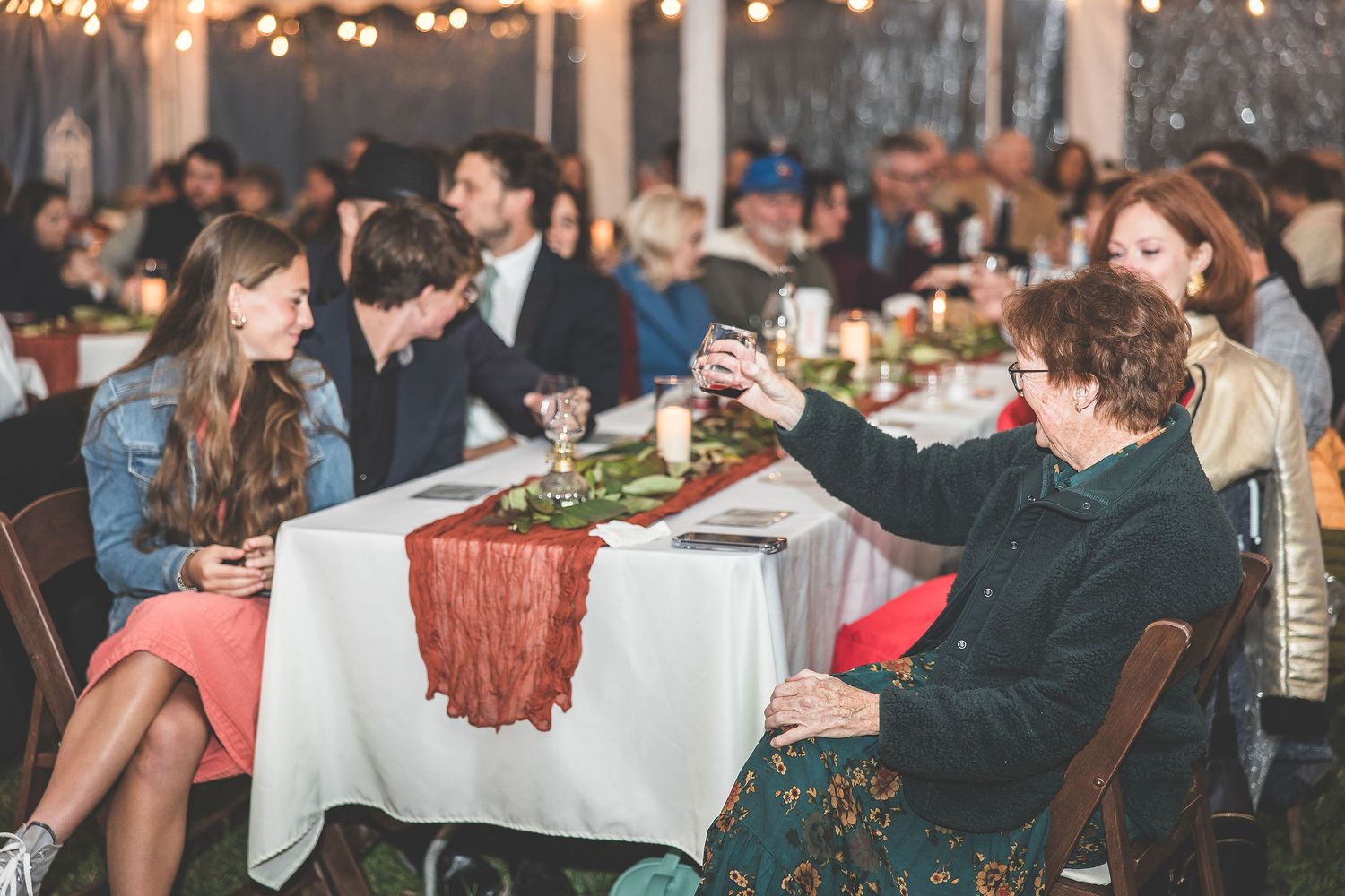 Wedding reception dining area with tables set under warm string lights.