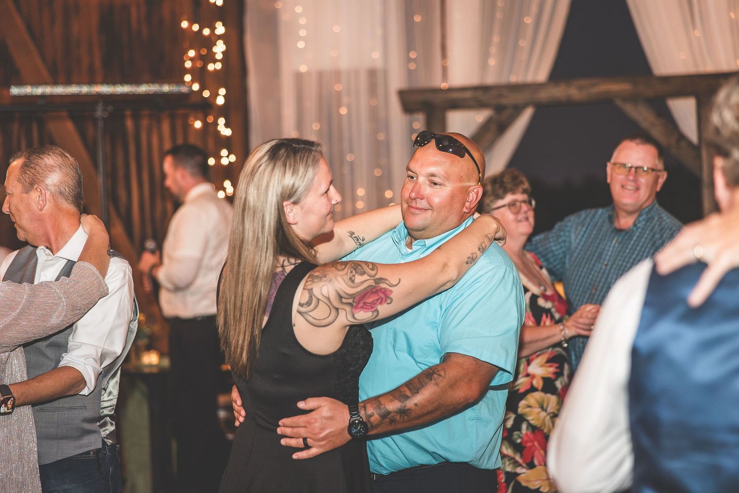 Guests enjoying group dances at a barn wedding reception with romantic lighting and decor.