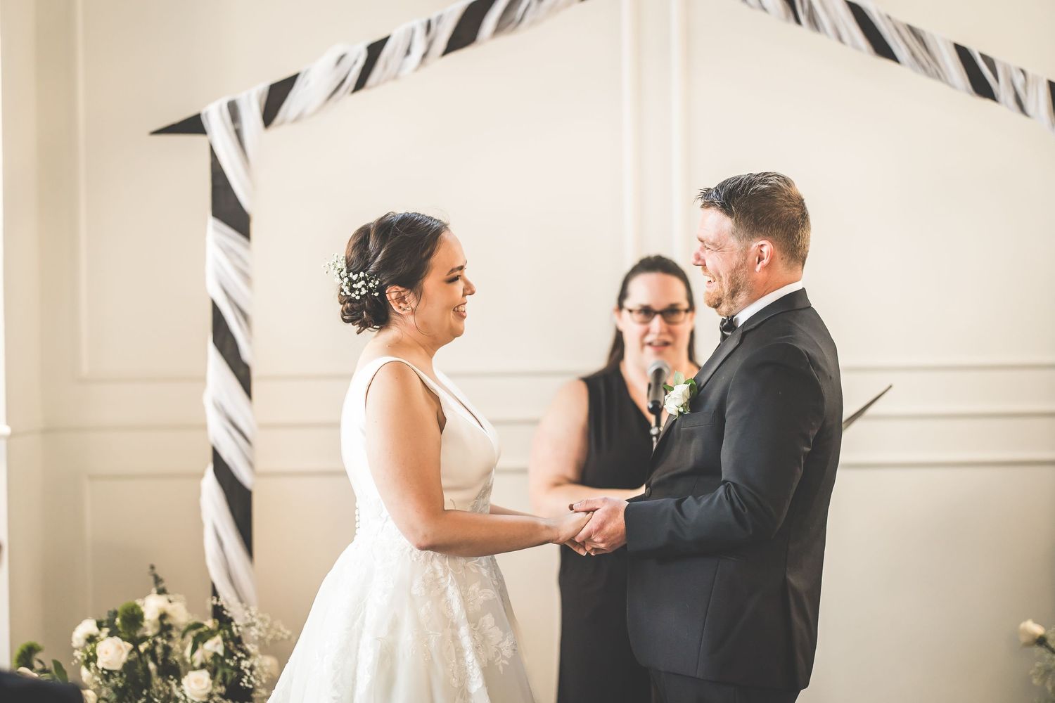 Wedding ceremony with black and white striped decorative elements against white paneled walls.
