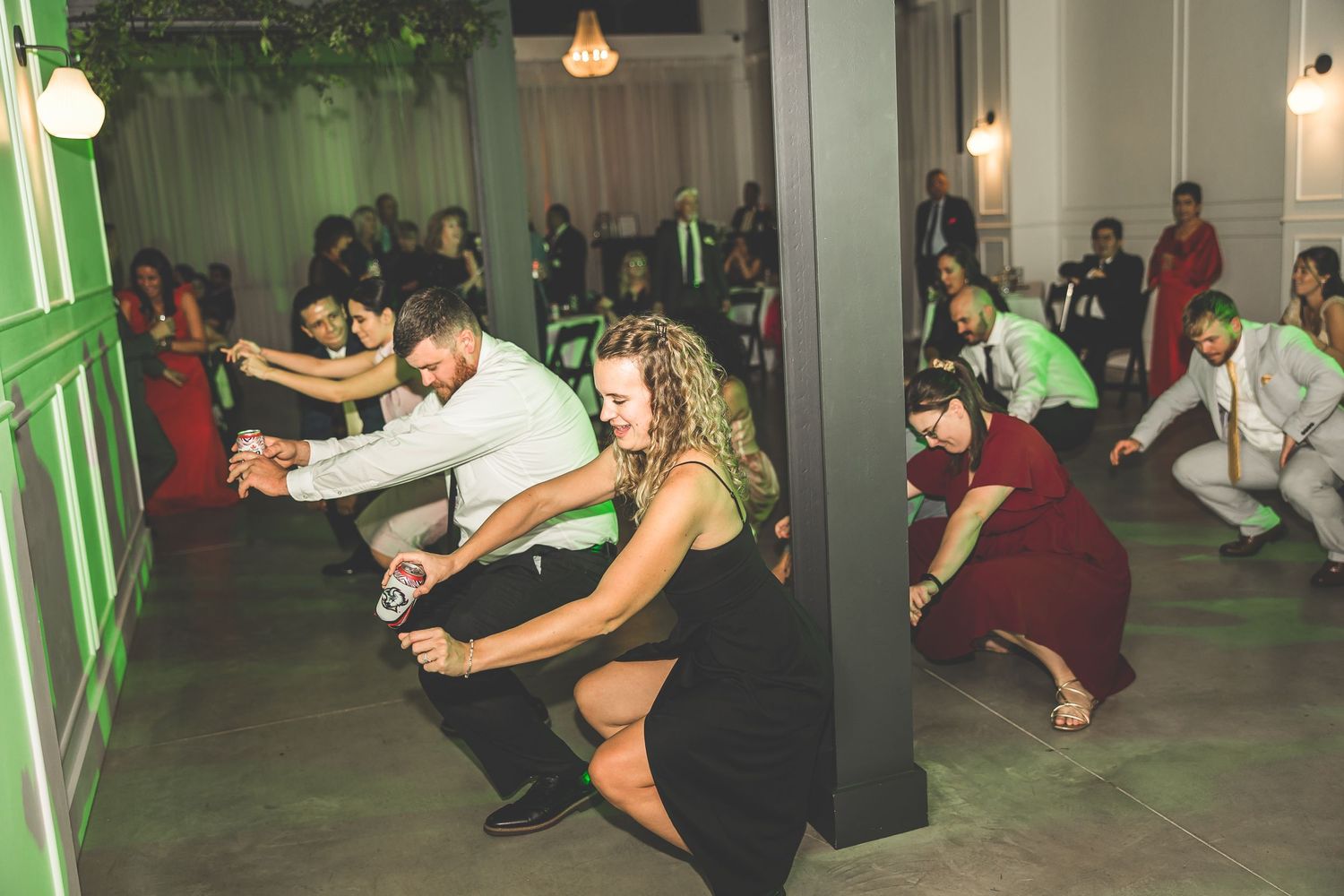 Wedding guests performing synchronized dance moves at a lively indoor reception.