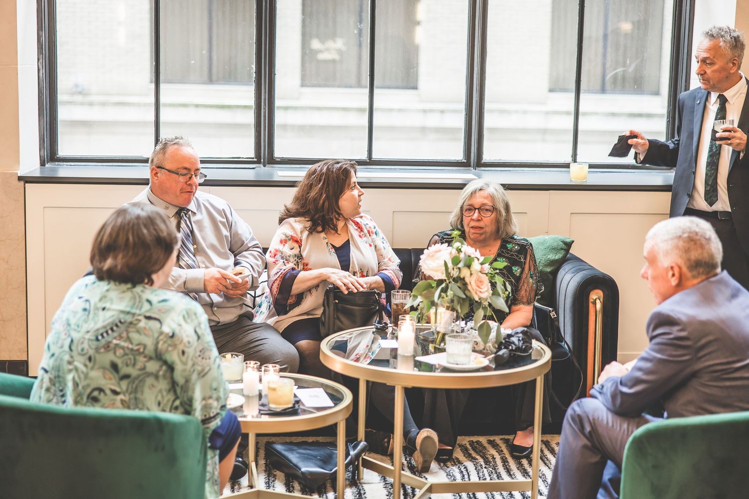 Wedding guests enjoying conversation at reception seating area with casual lounge furniture.