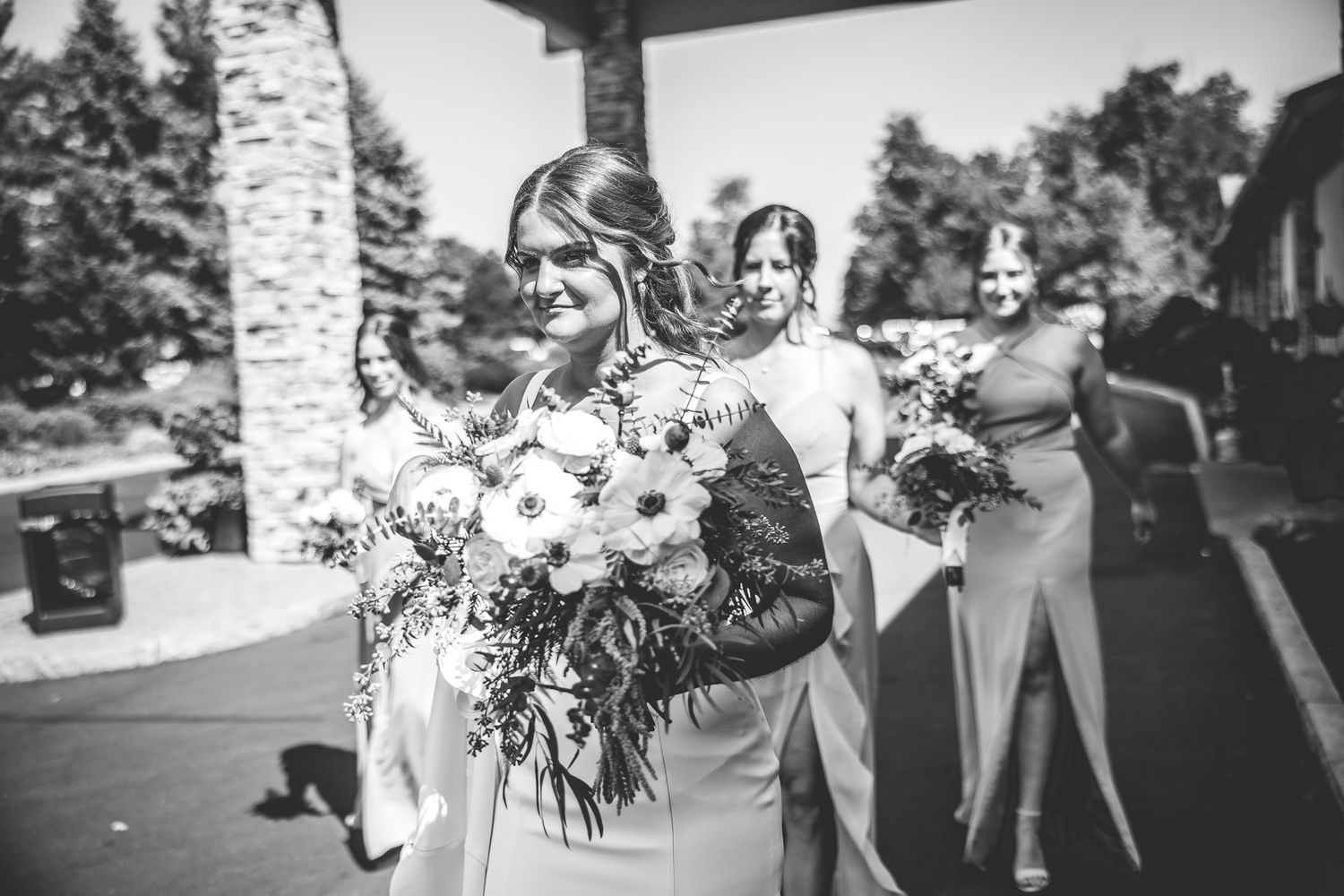 Black and white photo of a wedding party celebrating outdoors with joyful expressions.