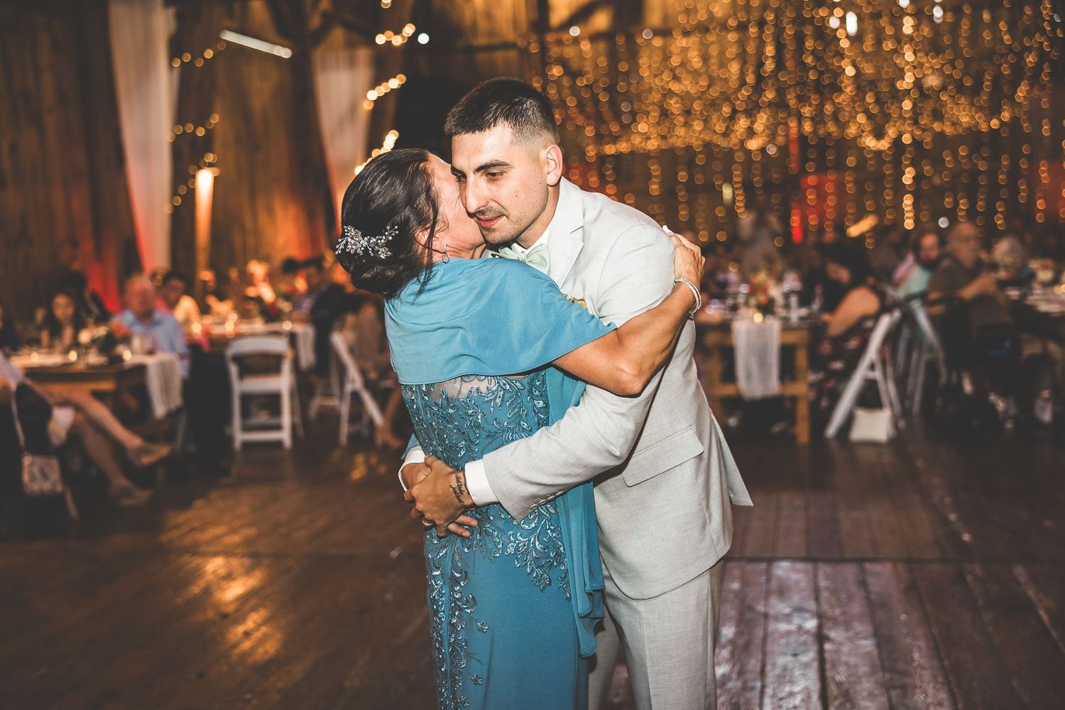 A tender dance embrace during a wedding reception in a beautifully decorated rustic venue.