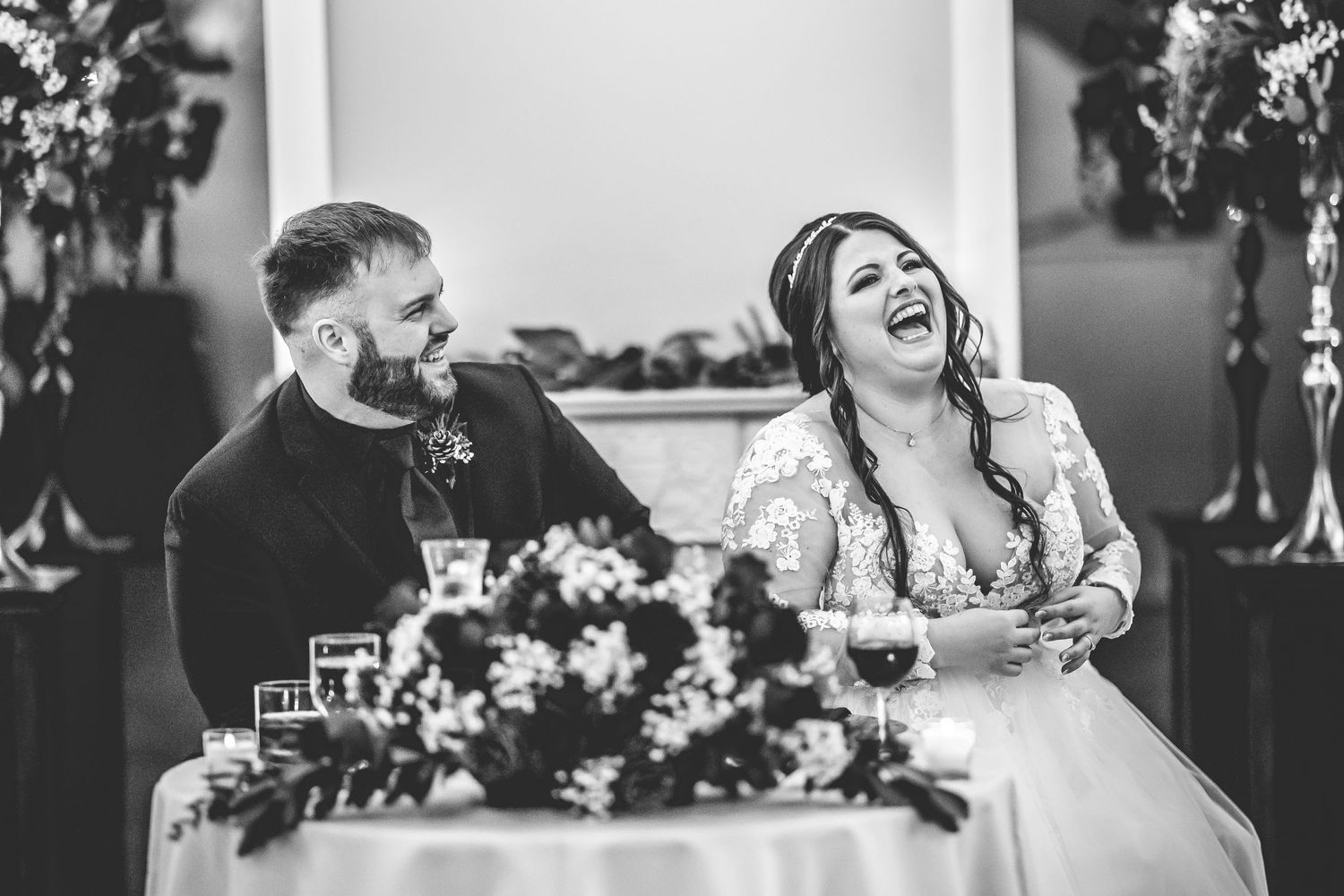 Joyful wedding celebration with guests laughing and dancing under decorative floral arrangements.